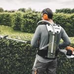 Man gebruikt HL 94 KC-E heggenschaar op steel om een heg te snoeien.